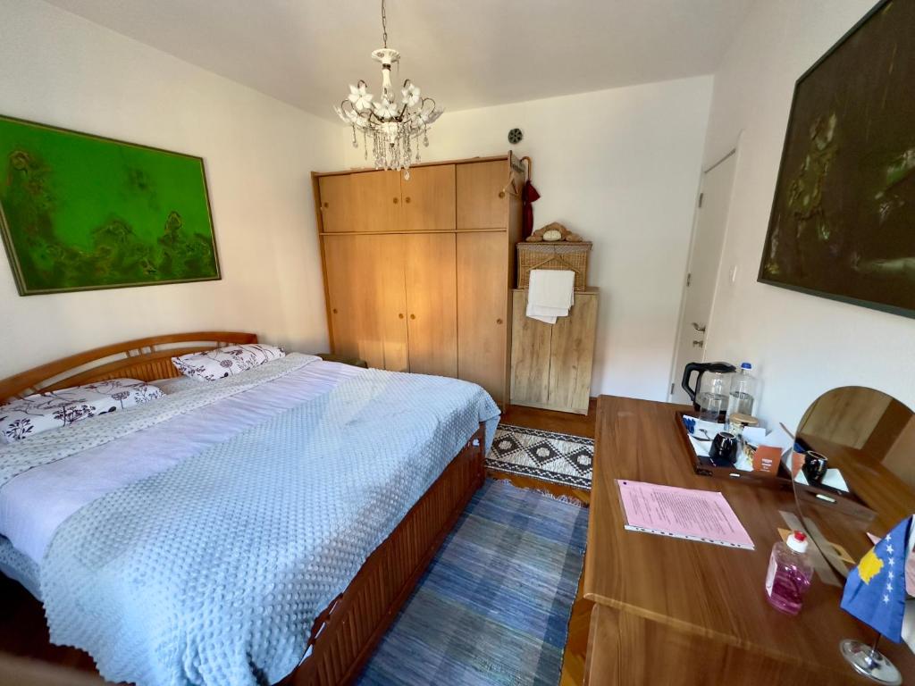 ein Schlafzimmer mit einem Bett, einem Tisch und einem Kronleuchter in der Unterkunft Convini Bed & Bathroom Homestay in Pristina