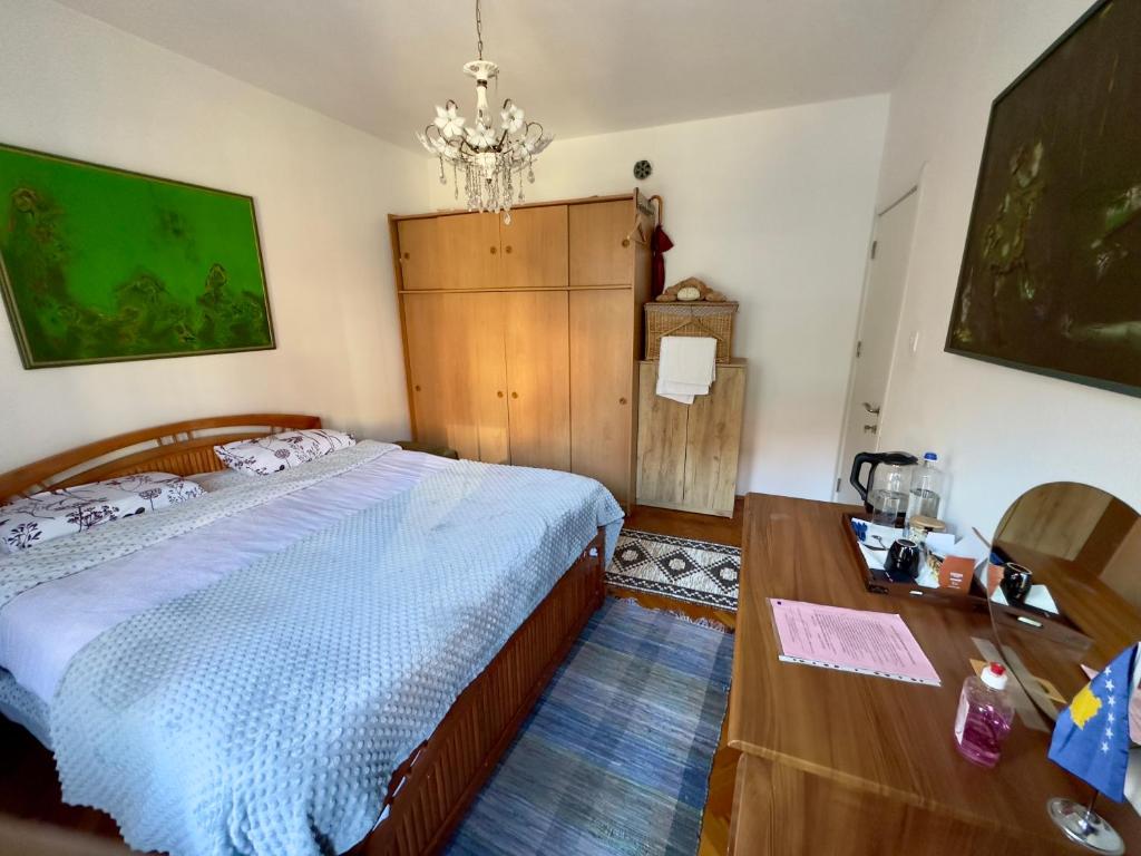 a bedroom with a bed and a table and a chandelier at Convini Bed & Bathroom Homestay in Pristina