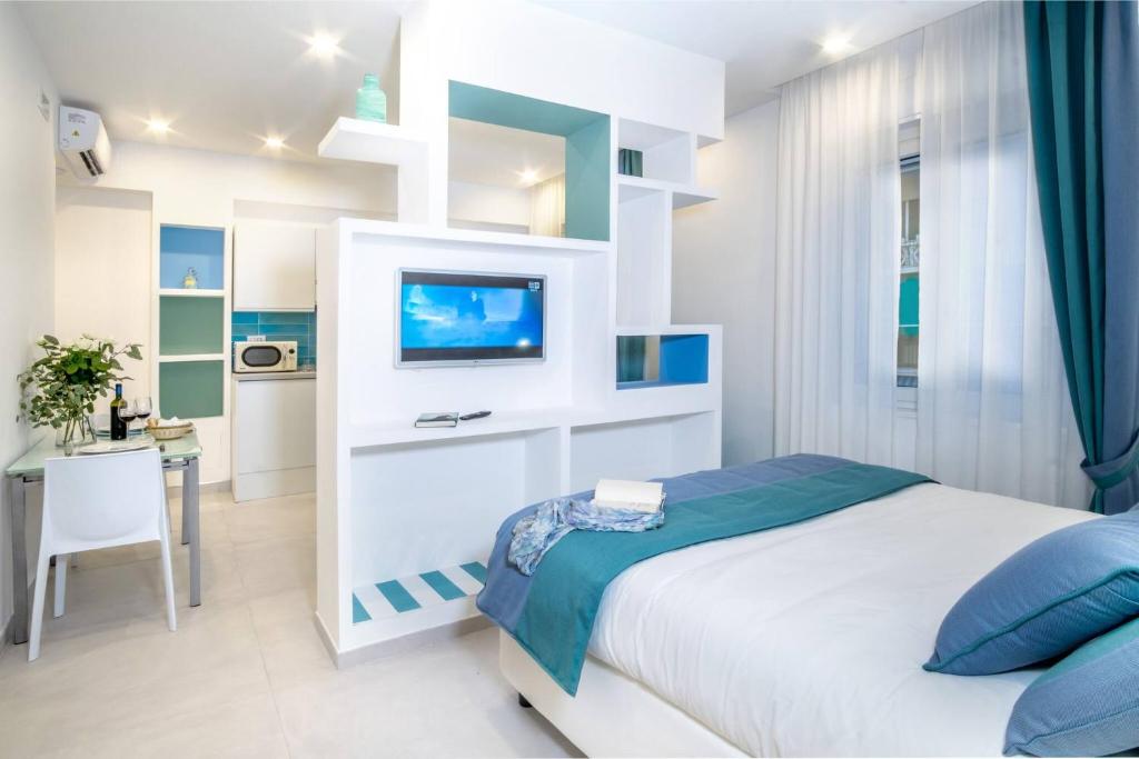 a white bedroom with a bed and a tv at Deluxe Apartment in Sorrento Centre in Sorrento