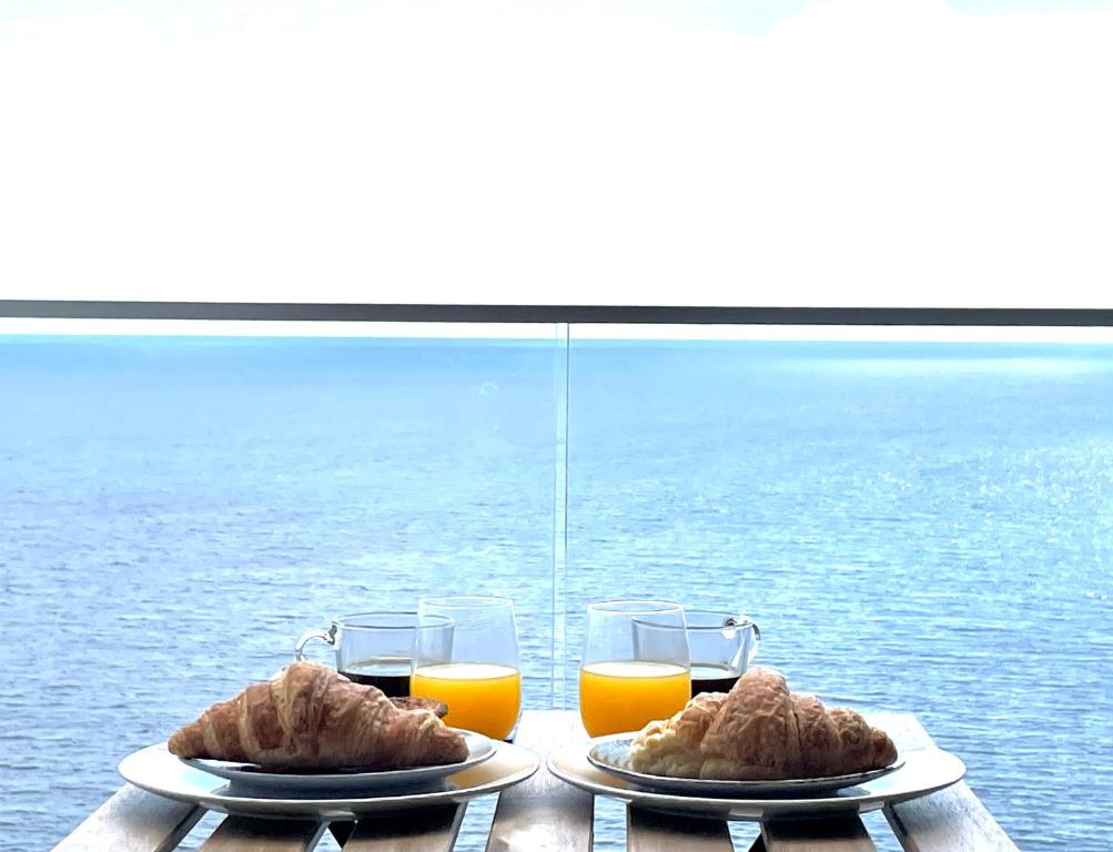 uma mesa com dois pratos de comida e dois copos de sumo de laranja em Ocean Cliff Apartment em Santa Cruz - Madeira
