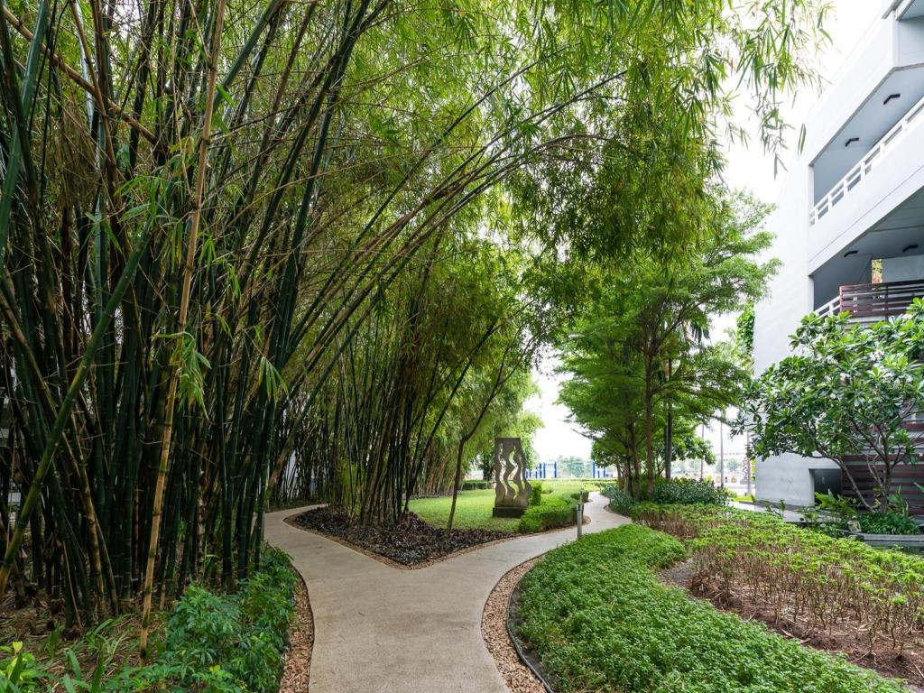 a walkway through a park with trees at Chatrium Hotel Riverside Bangkok in Bangkok