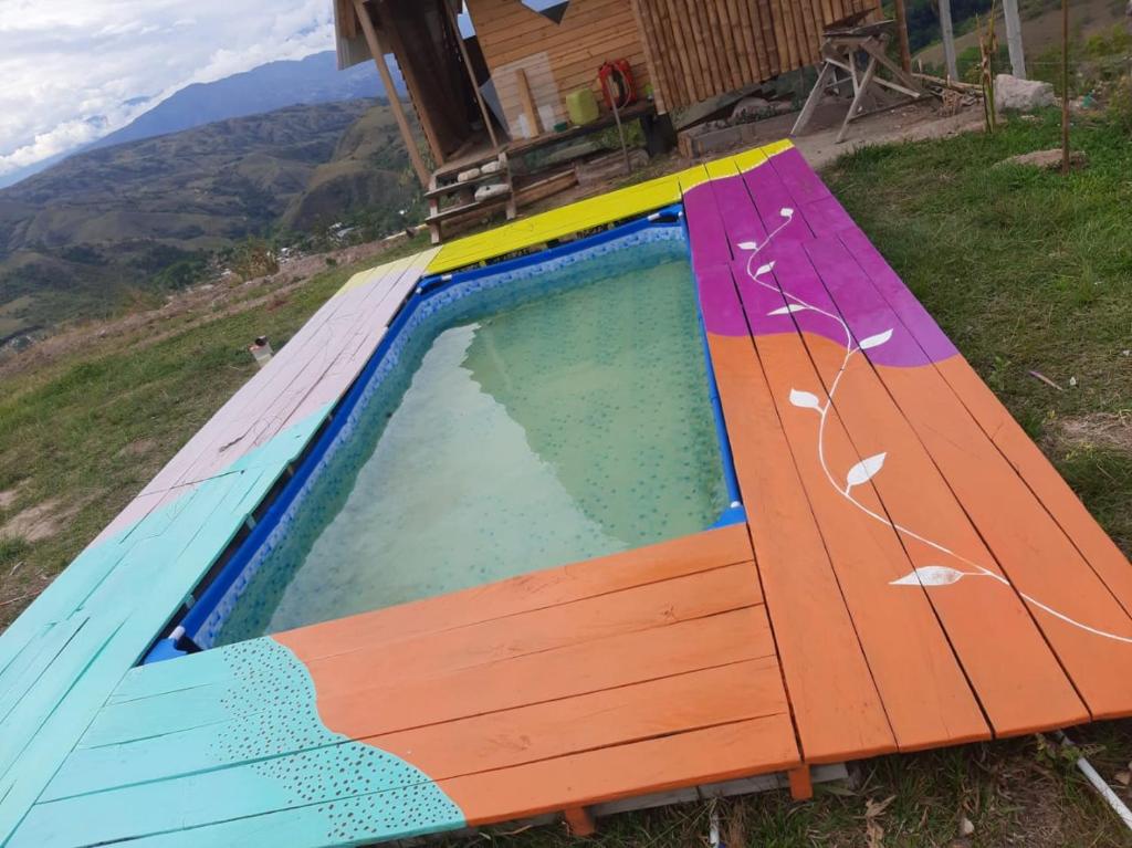 a swimming pool with a wooden bench in front of a house at Los Nevados Ecolodge in Gigante