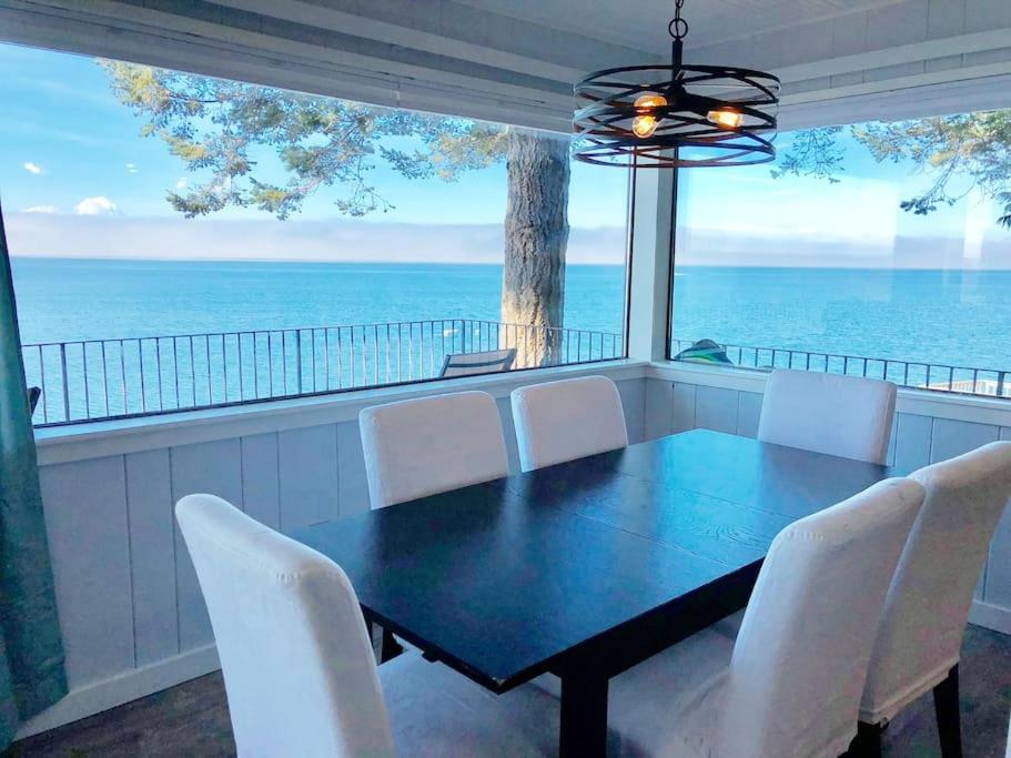 a dining room with a table and chairs and the ocean at Breezy Point Hideout BY Betterstay in Saratoga Shores
