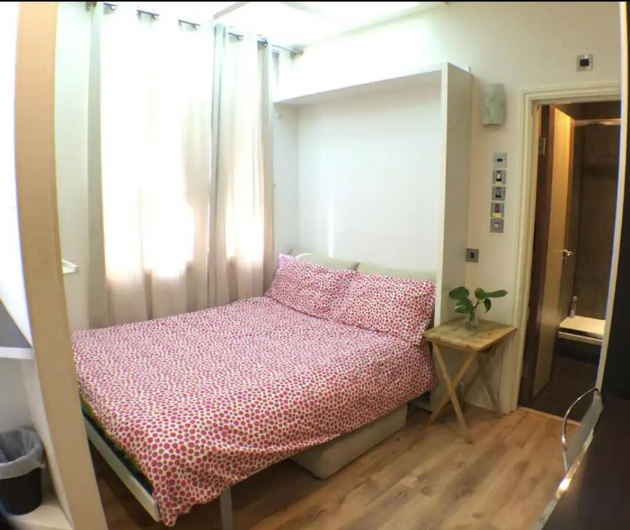 um quarto com uma cama com lençóis cor-de-rosa e uma janela em Soho China Town Rooms em Londres