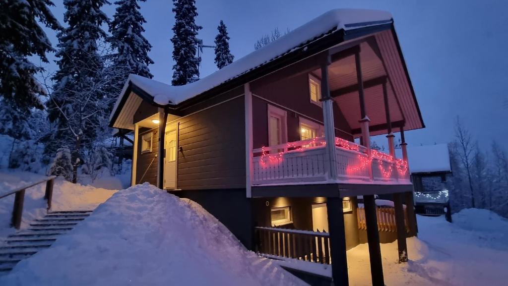 una cabaña en la nieve con luces de Navidad en el balcón en Villa Magnolia 1 Himos, en Jämsä