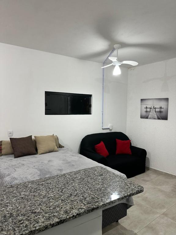 a bedroom with a bed and a black chair at apartamento Praia do Campeche, Jardim Eucaliptos in Florianópolis