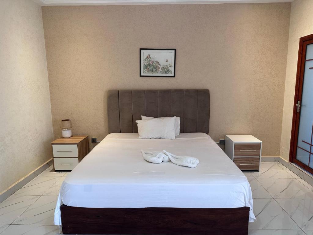 a bedroom with a large bed with two shoes on it at Apartments Plaza Hotel in Kololi