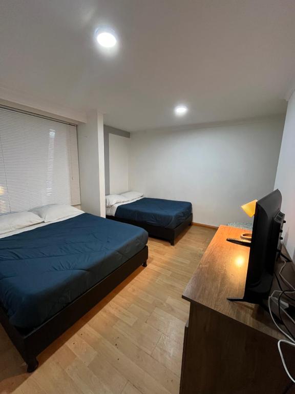 1 dormitorio con 2 camas, escritorio y TV en Way Maker sede 2, en Bogotá