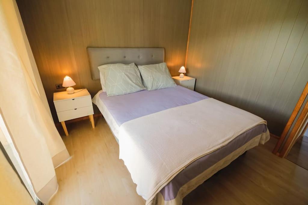 - une chambre avec un grand lit et 2 tables de chevet dans l'établissement Moderna Cabaña en Villarrica, à Villarrica