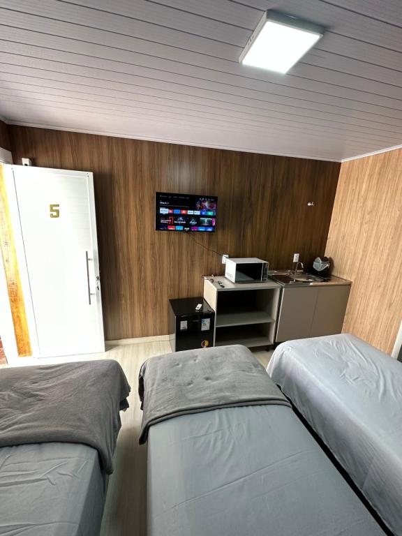 a hospital room with two beds and a tv on the wall at Loft Lux 5 in Chapecó
