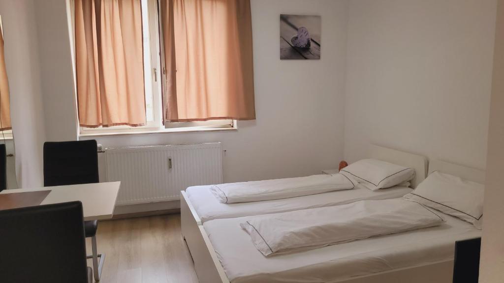 ザールブリュッケンにあるSaarbrücken City Apartmentsのベッド2台、テーブル、窓が備わる客室です。