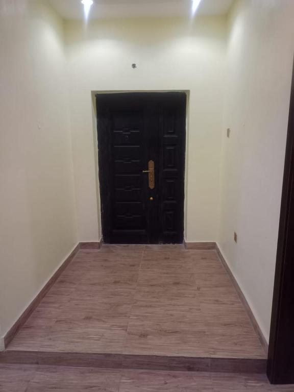 a black door in a white room with a wooden floor at Berkley House in Lagos