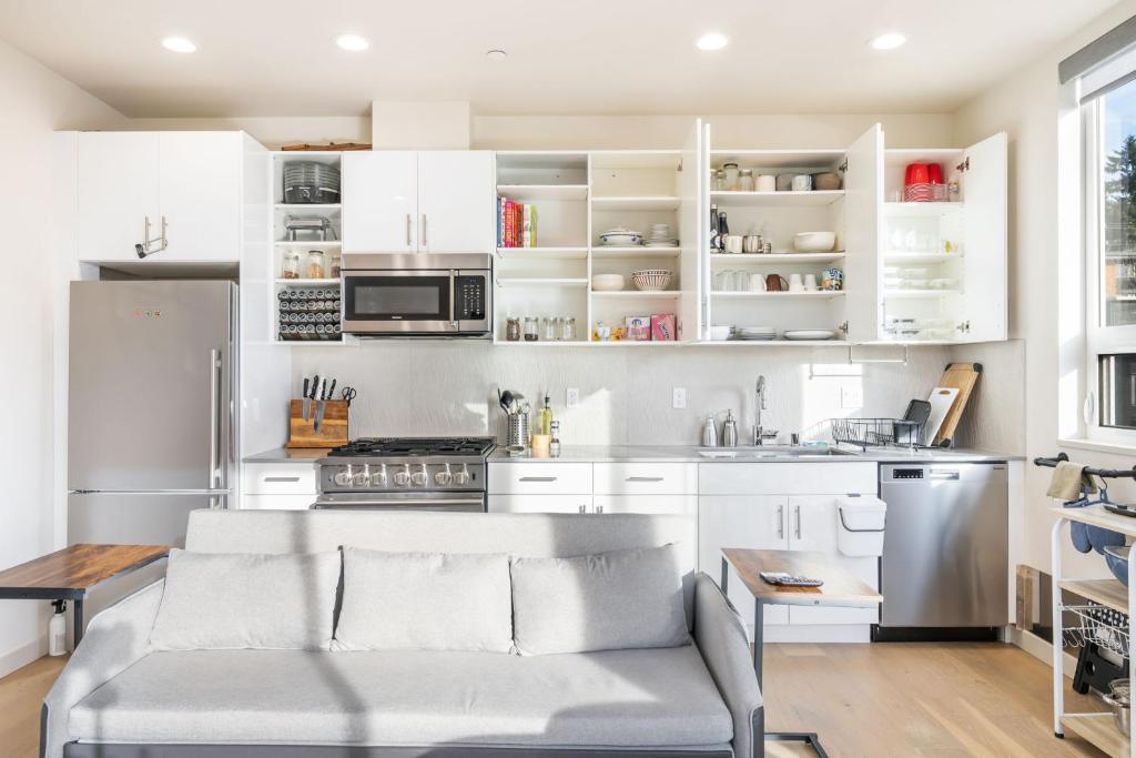 a kitchen with white cabinets and a couch in a room at Modern & Cozy New Townhome; Heart of Fremont in Seattle