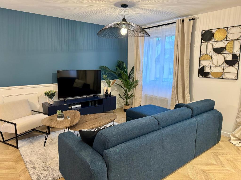 un salon avec un canapé bleu et une télévision dans l'établissement L'escale Versaillaise, à Saint-Cyr-lʼÉcole