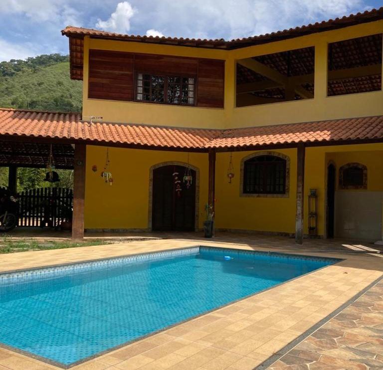 una piscina frente a una casa en Recanto Casa Amarela, en Miguel Pereira