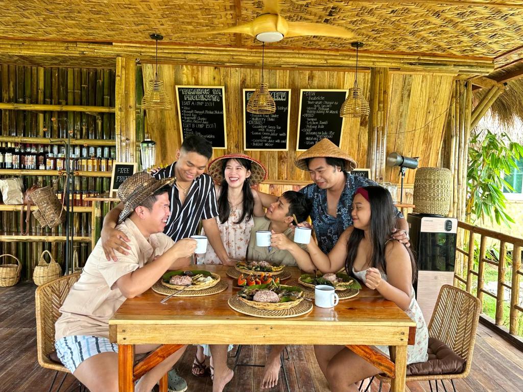 a group of people sitting around a wooden table at Joseph Agricultural Farm in Ubay