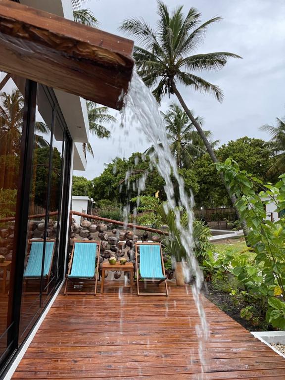 a water fountain on a deck with two chairs at CosyBe Villas in Inhambane