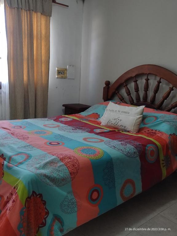 Una cama con un edredón colorido y una almohada. en Mis Vacaciones en Necochea