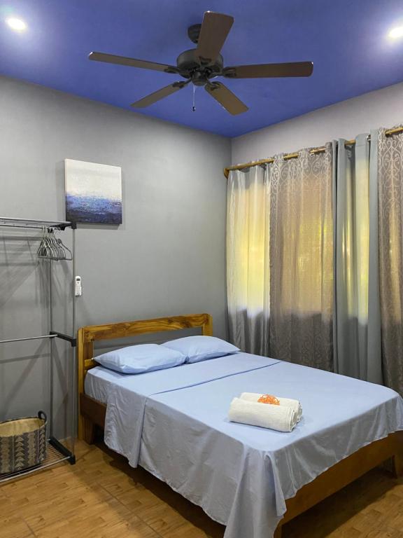 Jazlyn Lodge & Tours في باكيرا: غرفة نوم مع سرير ومروحة سقف