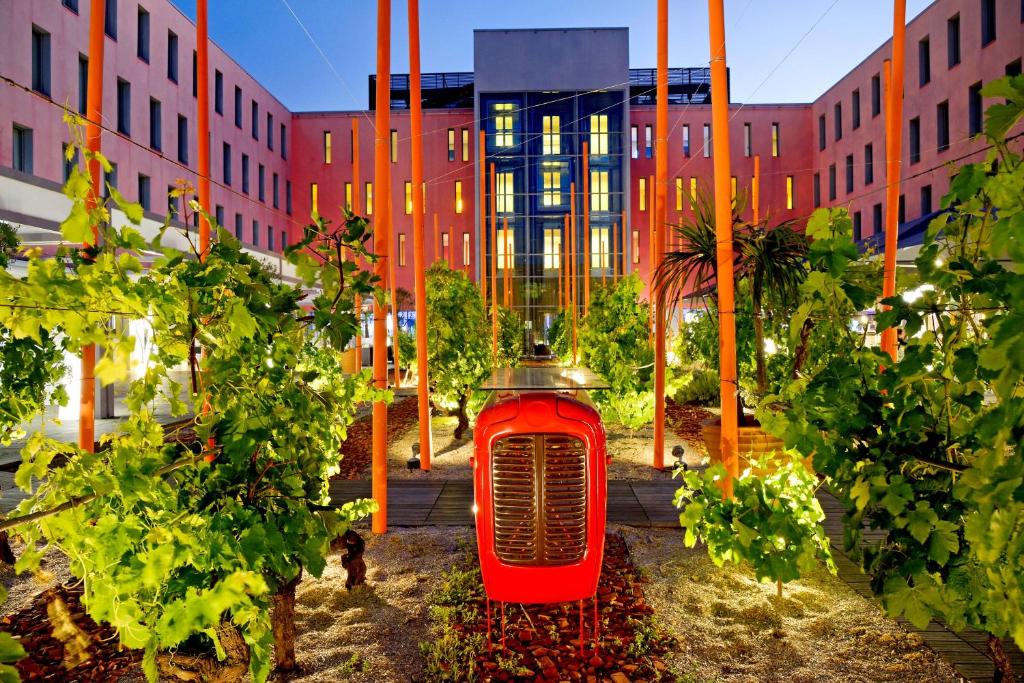 Une voiture rouge au milieu de quelques arbres dans l'établissement Radisson Blu Hotel Toulouse Airport, à Blagnac