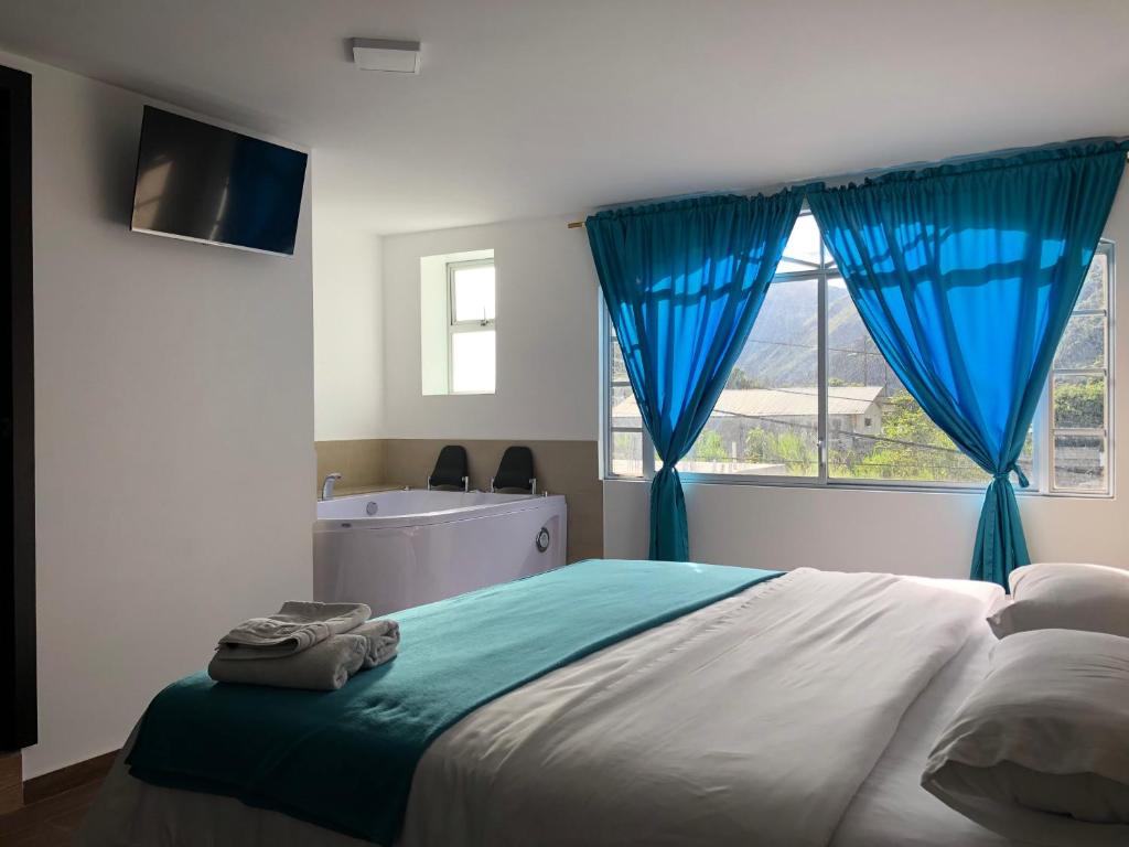 a bedroom with a bed with blue curtains and a window at First Class Hotel en Baños - Ciudad Volcan in Baños