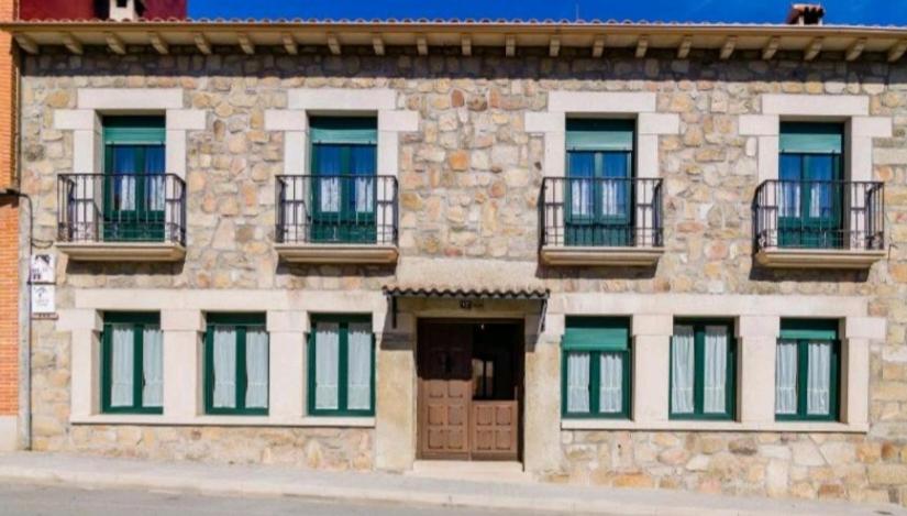 un edificio de piedra con ventanas y balcones. en Casas Rurales TIO CLAUDIO I y II, en El Barraco