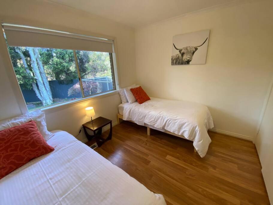 sypialnia z dwoma łóżkami i obrazem byka na ścianie w obiekcie Beautiful 3BR Home by Dandenong Creek w mieście Bayswater