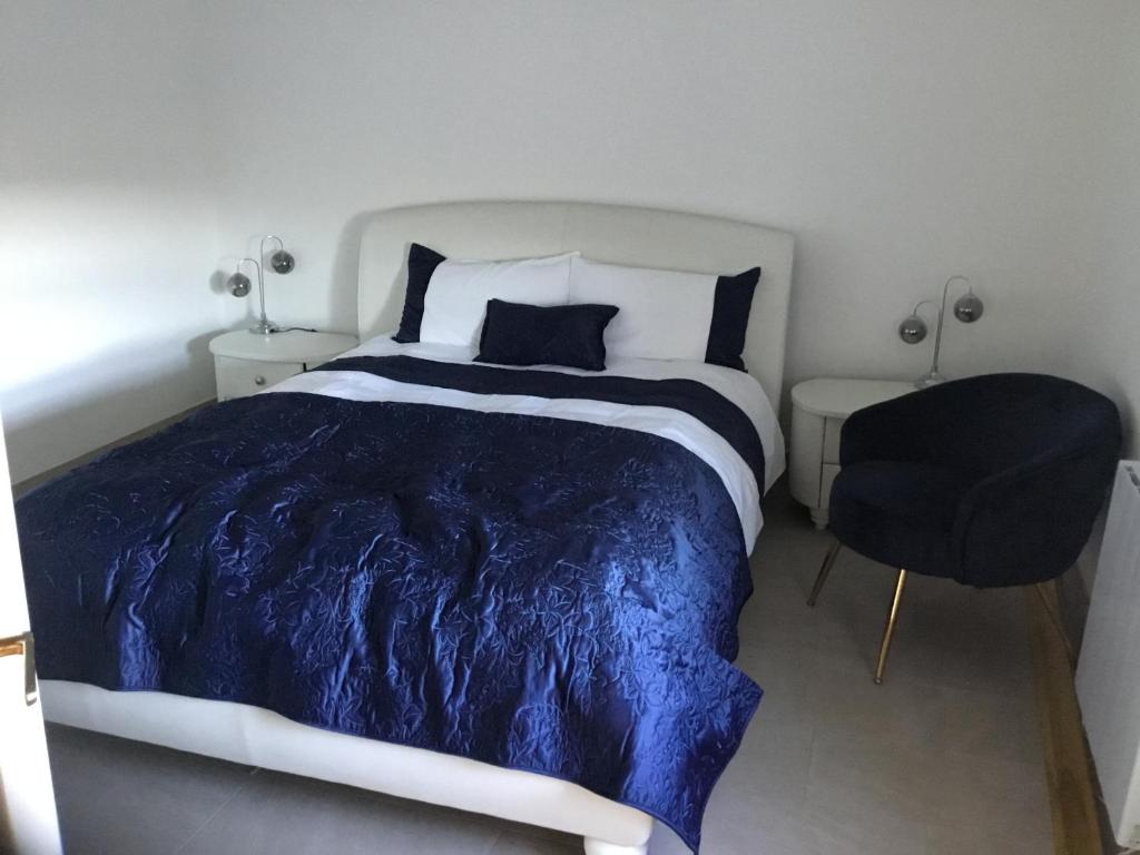 ein Schlafzimmer mit einem Bett mit einer blauen Bettdecke und einem Stuhl in der Unterkunft Cosy Cottage Broadford in Broadford
