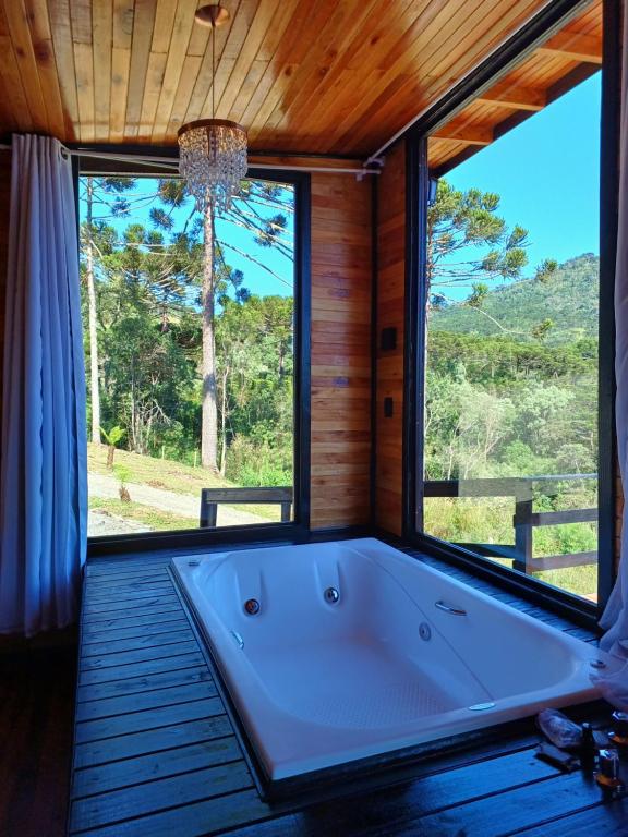 a large tub in a room with a large window at Recanto do Ipê (cabana 02) in Urubici