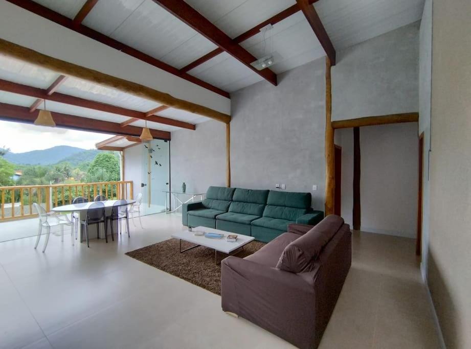 a living room with a couch and a table at Casa 3 suítes vista natureza in Ubatuba