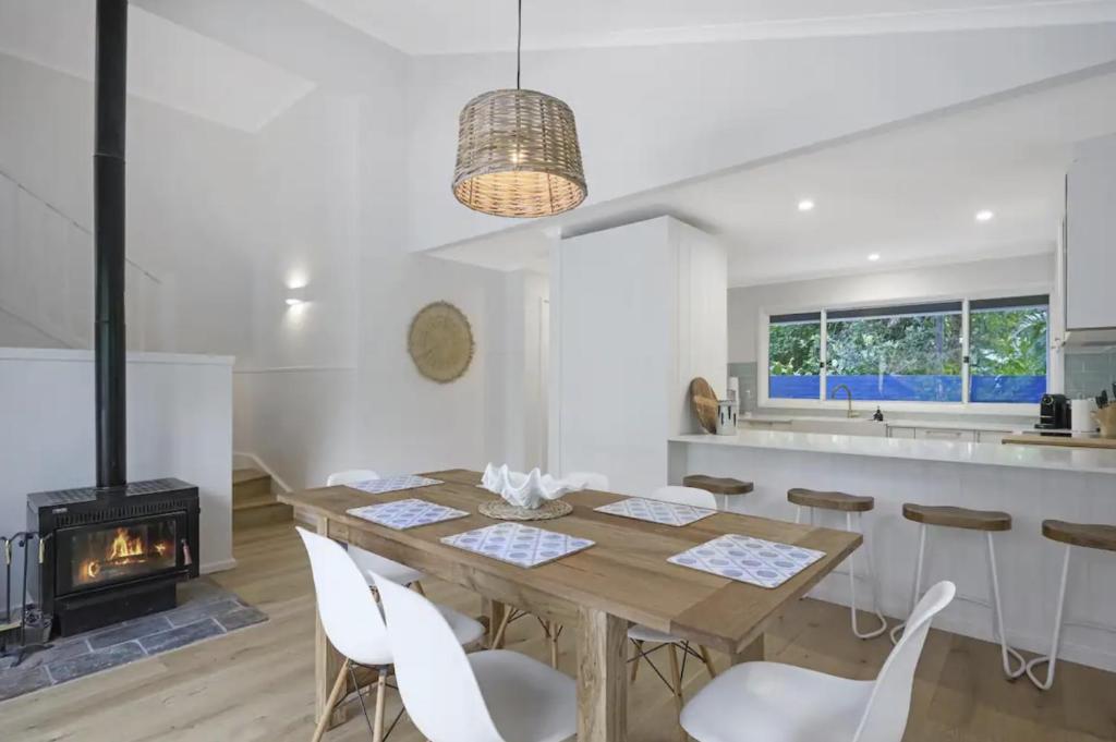 Macmasters BeachにあるFamily Friendly Beach House - 5mins walk to the beachのダイニングルーム(木製テーブル、暖炉付)