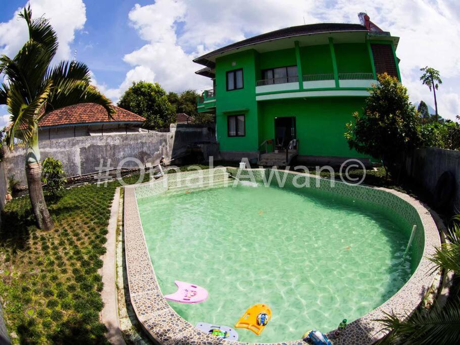 a swimming pool in front of a green house at Omah Awan at Desa Wisata Petik Jeruk Selorejo in Sengon
