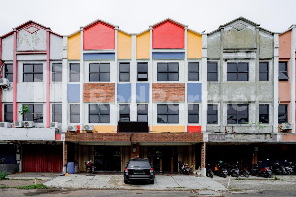 um edifício colorido com um carro estacionado na frente em Hotel Capital Cikokol RedPartner em Kebonnanas