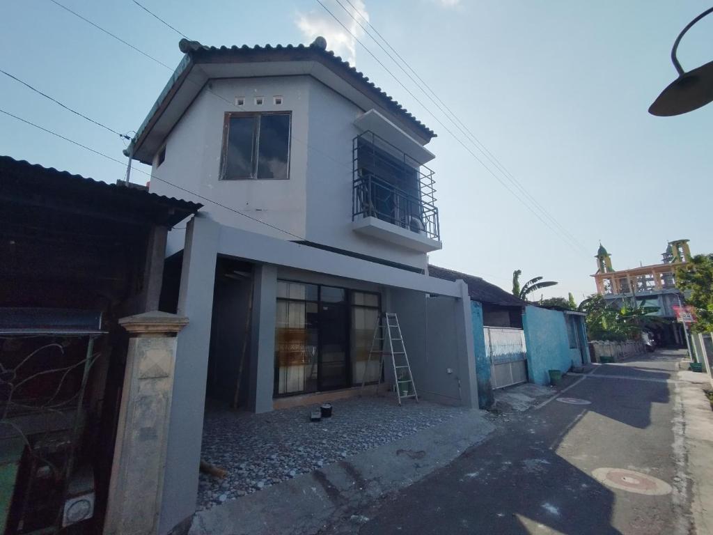 une maison blanche avec une échelle devant elle dans l'établissement RedDoorz at DeAmartaLoka Colomadu Solo, à Colomadu