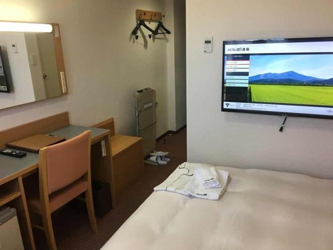 um quarto com uma grande televisão pendurada na parede em Hotel Alpha-One Sakata em Sakata