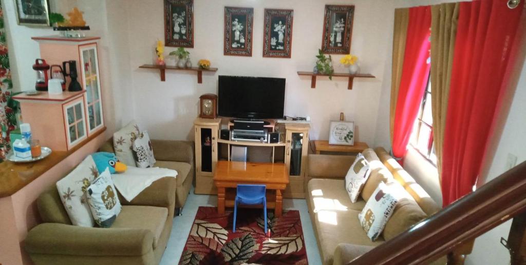 een woonkamer met een bank en een tv bij Charming Getaway @ The City of Pines in Baguio