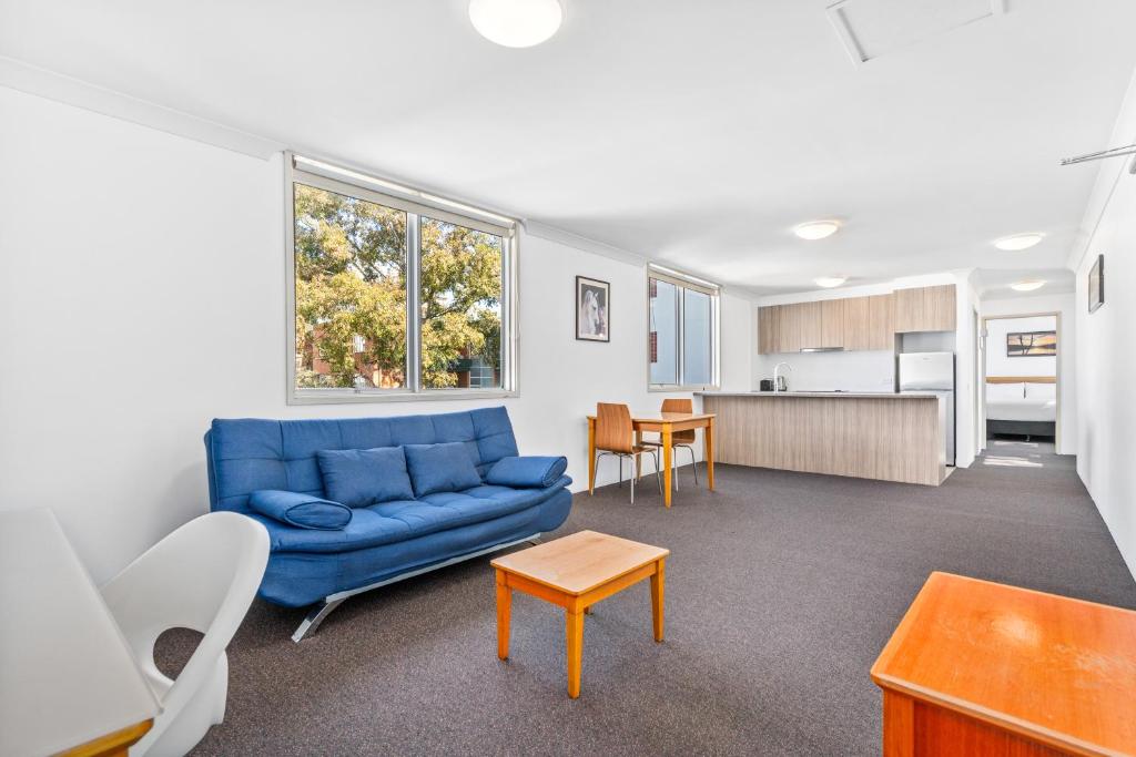 a living room with a blue couch and a kitchen at APX Parramatta in Sydney