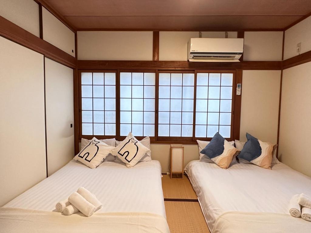 two beds in a room with two windows at Yuyu House Kohama Teru - Vacation STAY 15334 in Osaka