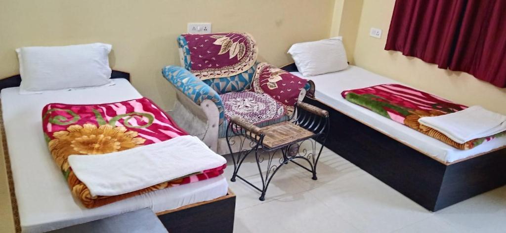 um quarto com duas camas e uma cadeira em RK GUEST HOUSE em Bodh Gaya