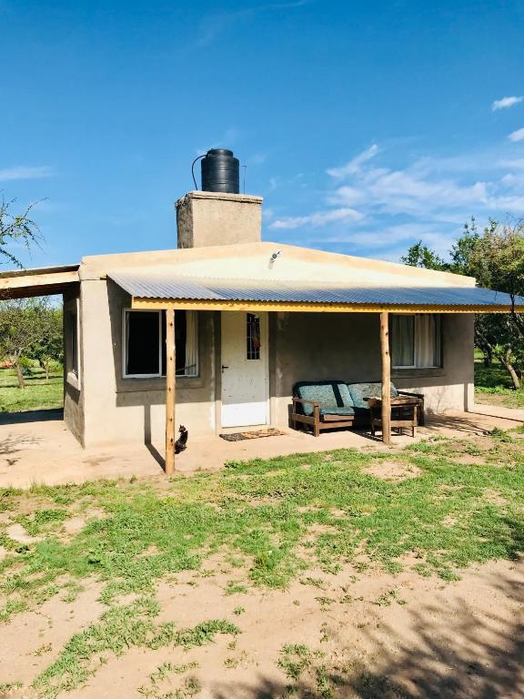 Una pequeña casa blanca con un porche y un banco. en El CAMPITO, en Cruz de Caña