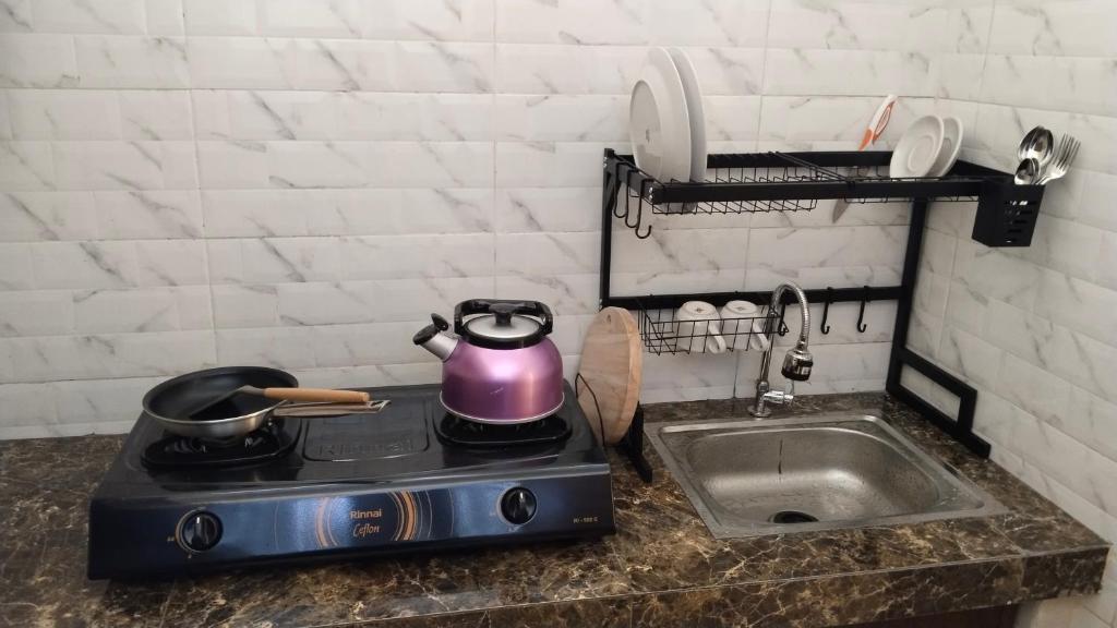 a tea kettle on top of a stove next to a sink at D'Natha Villa Ubud in Ubud