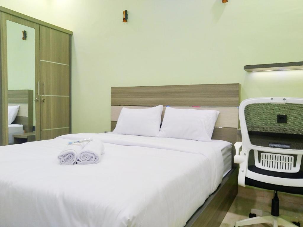 1 dormitorio con 1 cama blanca grande y 1 silla en Shiva Home Syariah RedPartner near Alun Alun Tegal, en Tegal