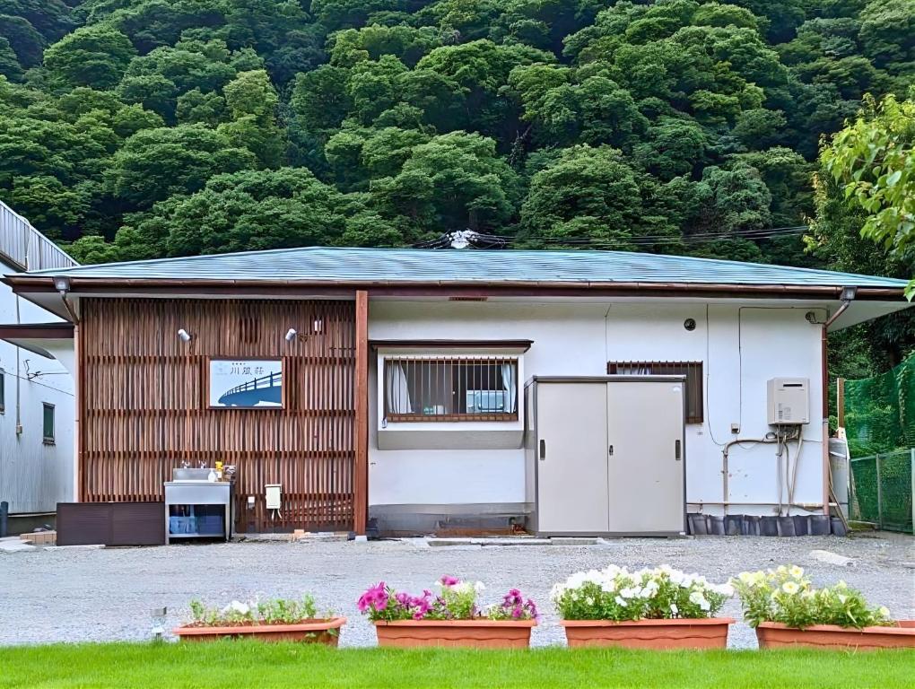 箱根湯本 川風荘 - Hakone Yumoto Kawakazesou في هاكوني: منزل صغير وامامه زهور
