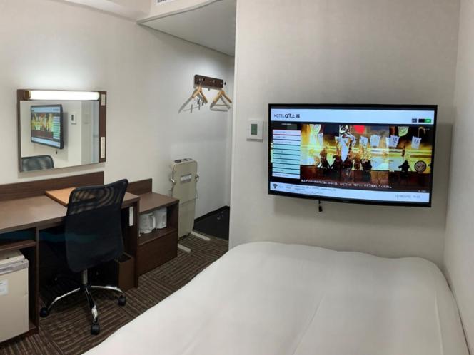 Hotel Alpha-One Joetsu في جويتسو: غرفة فندقية فيها سرير ومكتب وتلفزيون
