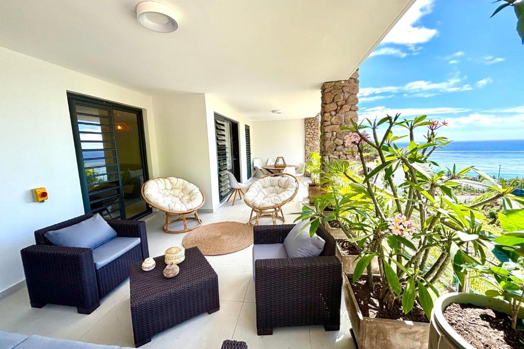 une terrasse avec des chaises et des tables et l'océan dans l'établissement Pacific cosy home Bougainvilliers, à Punaauia