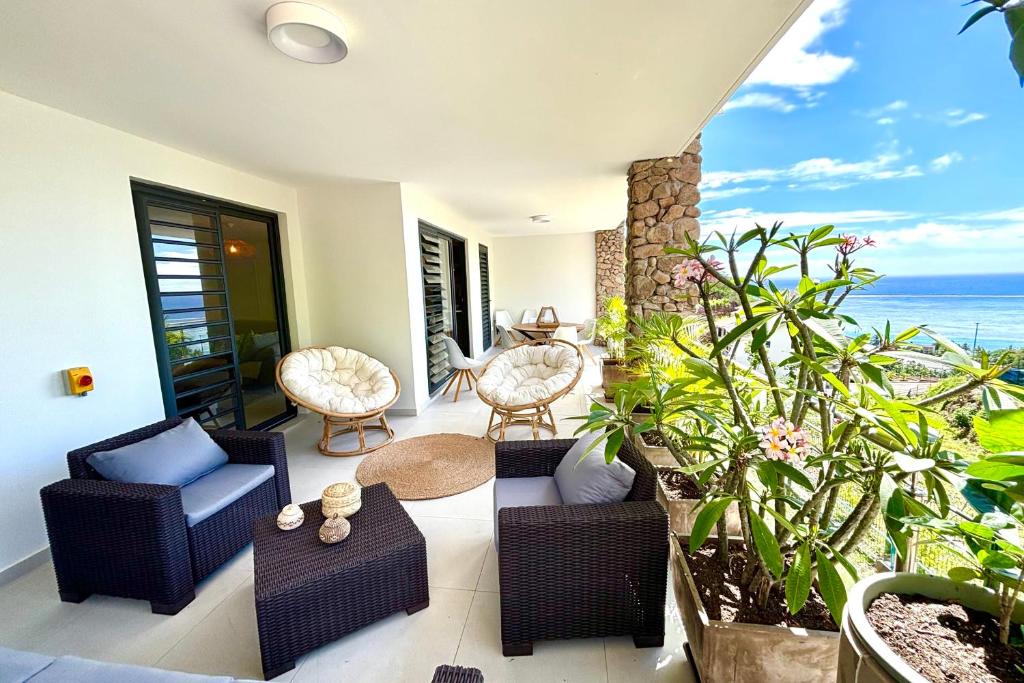 a patio with chairs and tables and the ocean at Pacific cosy home Bougainvilliers in Punaauia