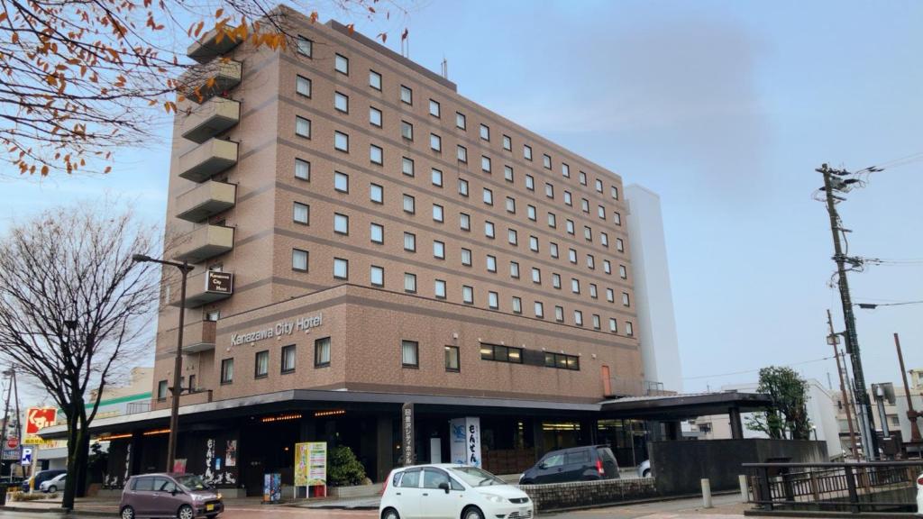 een groot gebouw met auto's geparkeerd voor het bij Kanazawa City Hotel in Kanazawa