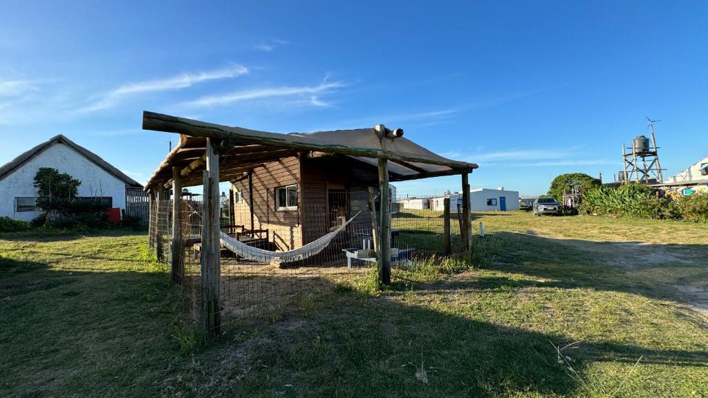Cabaña de madera con hamaca en un campo en Cabo Polonio - Rancho 66, en Cabo Polonio
