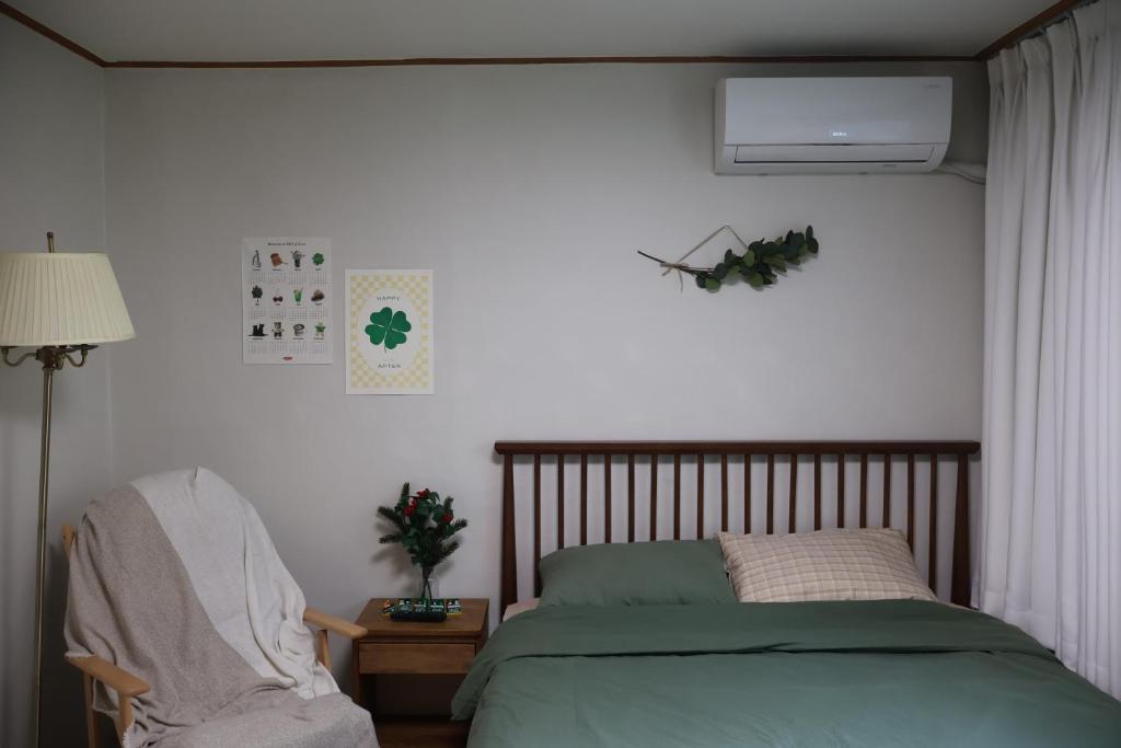ein Schlafzimmer mit einem grünen Bett und einem Stuhl in der Unterkunft Clover Stay, 2BR,1BA,mapo, free-wifi, in Seoul