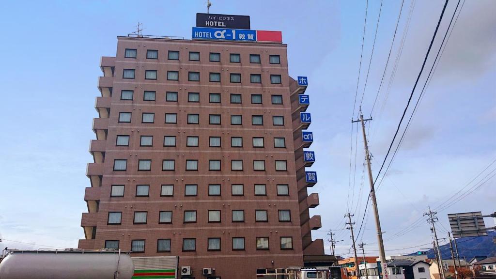 ein hohes Gebäude mit einem Schild darüber in der Unterkunft Hotel Alpha-One Tsuruga in Tsuruga